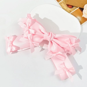 Detail of light pink satin bow hair clip with decorative ribbons on a French style background