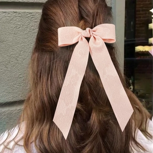 Elegante fermaglio per capelli con fiocco rosa e motivo jacquard su una modella
