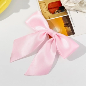 Detailed close-up of a pink satin bow hair clip featuring smooth glossy texture