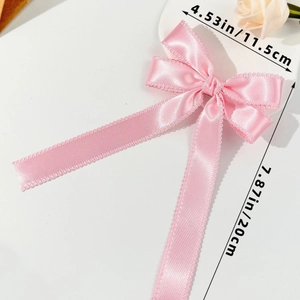 Détail du nœud papillon en satin rose avec dimensions et finition des bords dentelés