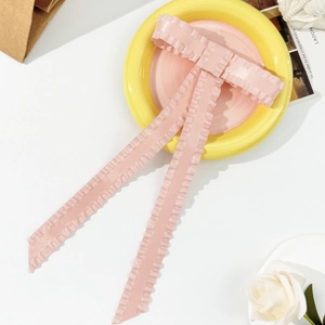 Close-up of pink ribbon hair clip with ruffled edges and elegant long streamers