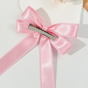 Détail du dos d'un nœud papillon en satin rose avec dentelle et pince crocodile métal
