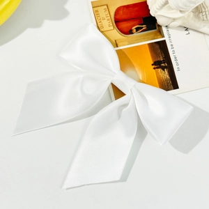 Detail of white satin bow hair clip showing smooth fabric texture and elegant craftsmanship