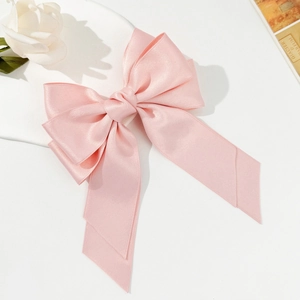 Detail view of pink satin bow hair clip with long streamers and elegant silk texture