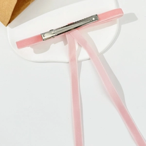 Detail showing the pink velvet ribbon hair clip with a sturdy silver metal duckbill grip