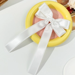 Détail d'un nœud papillon en satin blanc avec dentelle sur une assiette pastel