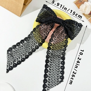 Detail view of large black lace hair bow clip with long ribbons and floral embroidery