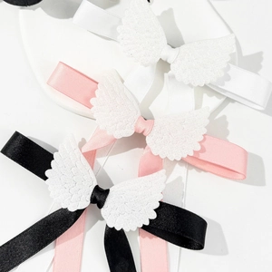Détail de pinces à cheveux ailes d'ange avec rubans en soie blanc, rose et noir