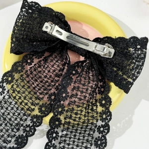 Detailed view of black lace bow hair clip featuring a sturdy metal spring clasp with engraving
