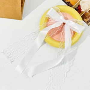Detail of elegant white lace bow hair clip with ribbons on decorative round plate