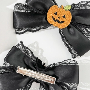 Detail view of black lace bows with orange glitter pumpkin for Halloween hair styling