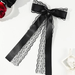 Detail of black satin bow hair clip with floral lace edges and long hanging ribbons