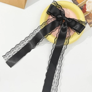 Elegant black lace bow hair clip with satin ribbons on a decorative ceramic plate