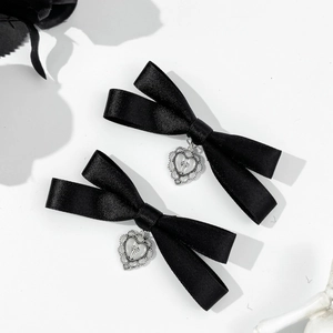 Detail of black satin bow hair clips featuring silver heart and cross metal charms
