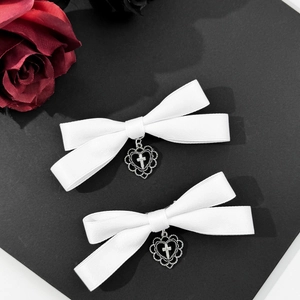 Macro view of white handmade bow hairpins with silver heart and cross pendants