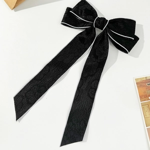 Detail of elegant black ribbon hair clip with jacquard texture and white trim accents
