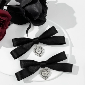 Detail of black satin bow hair clips with silver heart cross pendants and rose decor