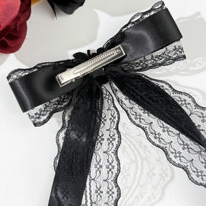 Detailed macro view of gothic black satin bow hair clip with lace and metal duckbill clip
