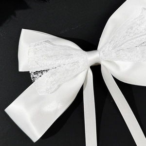 Close-up of white lace ribbon hair clip showing high-gloss satin texture and fine mesh lace