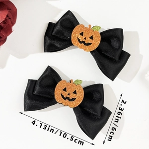 Close-up of black satin Halloween bow clips with orange glitter pumpkin centers