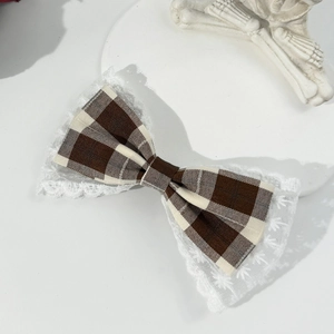 Detail of vintage houndstooth hair bow clip with delicate lace edges on white background