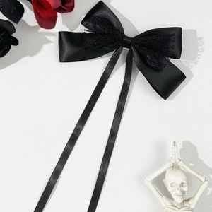 Detail view of a gothic black satin bow hair clip with lace edges and long flowing ribbons