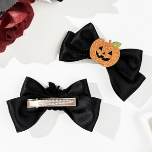 Detail of Halloween hair clips with black ribbon bows and glittery orange pumpkin motifs