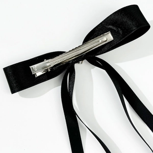 Detail view of the secure silver metal alligator clip on a black satin ribbon hair bow