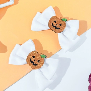 Close-up of white Halloween hair bows featuring sparkly orange sequined pumpkin centers