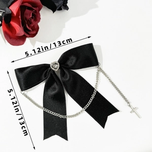 Detail of gothic black satin bow hair clip with heart rhinestone and cross chain pendant