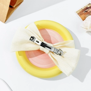 Detail of the elegant beige ribbon hair clip showing the metallic spring clip mechanism