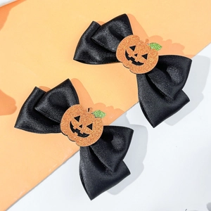 Close-up of black satin hair bows with glitter pumpkin charms for Halloween party