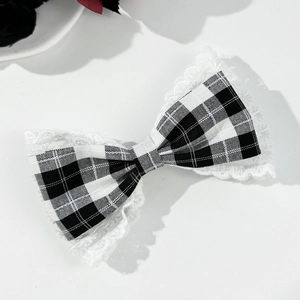Close-up of houndstooth bow hair clip with delicate white lace trim on white background