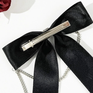 Close-up of gothic bow hair clip with silver chains and metallic alligator clip on back