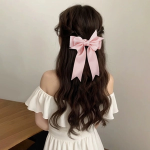Barrette à cheveux avec nœud rose et longs rubans sur cheveux ondulés pour un look élégant