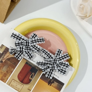 Close-up of sweet checkerboard bow hair clips in a ceramic dish with decorative card