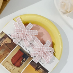 Detail of pink gingham bow hair clips with scalloped edges on a decorative ceramic tray