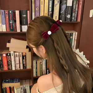 Elegant deep red velvet bow hair clips with white pearls shown on a brunette model
