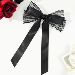 Nœud de cheveux gothique noir avec dentelle et longs rubans sur un fond blanc épuré