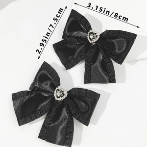Detailansicht von zwei schwarzen Satin-Haarschleifen mit Strass-Herz und Größenangaben