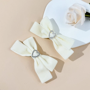 Detail of cream velvet bow hair clips with sparkling heart rhinestones on a tray