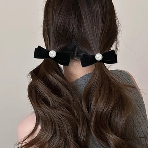 Close-up of elegant black velvet bow hair clips with pearls worn on twin low ponytails