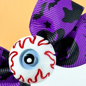 Close-up of Halloween purple bow hair clip featuring a realistic eyeball and black bats