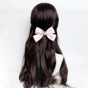 Pink satin bow hair clip with rhinestone heart on black wavy hair for women