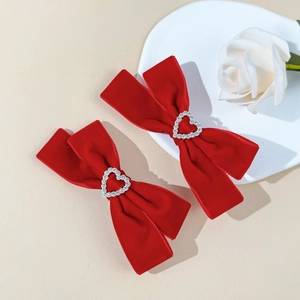 Detailed macro view of red velvet bow hair clips with heart-shaped crystal center rhinestones