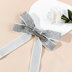 Detail of silver sequin bow hair clip with elegant long white satin ribbons and metal clip