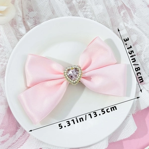 Detailed size view of pink satin bow hair clip with rhinestone heart and pearl center