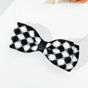 Détail d'une pince à cheveux à nœud damier noir et blanc en tissu tweed texturé