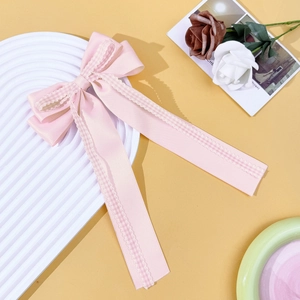 Détail d'un nœud en satin rose avec bordure à froufrous à carreaux sur plateau texturé blanc
