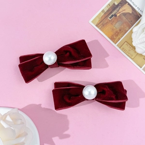 Detail view of velvet bow hair clips with pearls on a decorative pink background